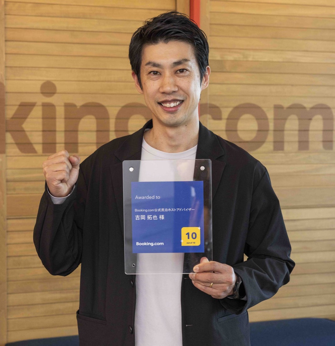 Booking.com 公式民泊ホストアドバイザーの盾を持つ吉岡拓也